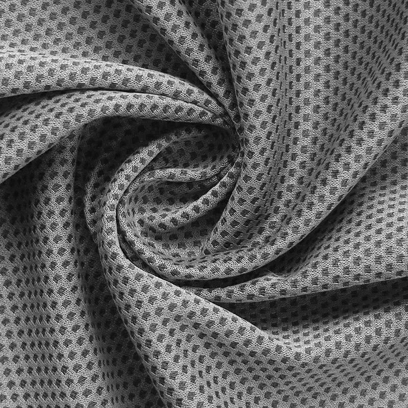 Close-up of twisted black and white textured cooling towel fabric with a repeating dot pattern.