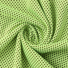 Close-up of twisted light green cooling towel fabric with a dark repeating dot pattern.