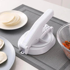 Dumpling Skin Press - White manual dough press on a placemat, with stacked dough wrappers, filled dumplings, and a filling bowl nearby