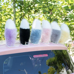Six plush car moving tail decorations stand in a row on a pink car roof, with white tips and bodies in purple, black, blue, pink, gray, and cream.