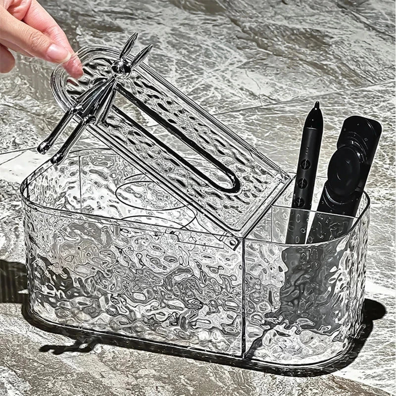 Tissue Box Holder - Clear textured tissue box with open lid lifted by a hand, holding a pen and remote in side compartment