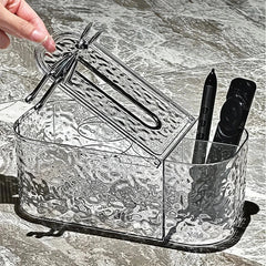 Tissue Box Holder - Clear textured tissue box with open lid lifted by a hand, holding a pen and remote in side compartment