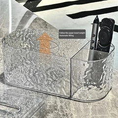 Tissue Box Holder - Open clear textured tissue box with auto-lift platform indicated by arrow, holding pen and remote in side compartment
