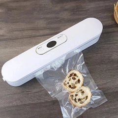White bag heat sealer on a wooden table next to sealed pastry snacks