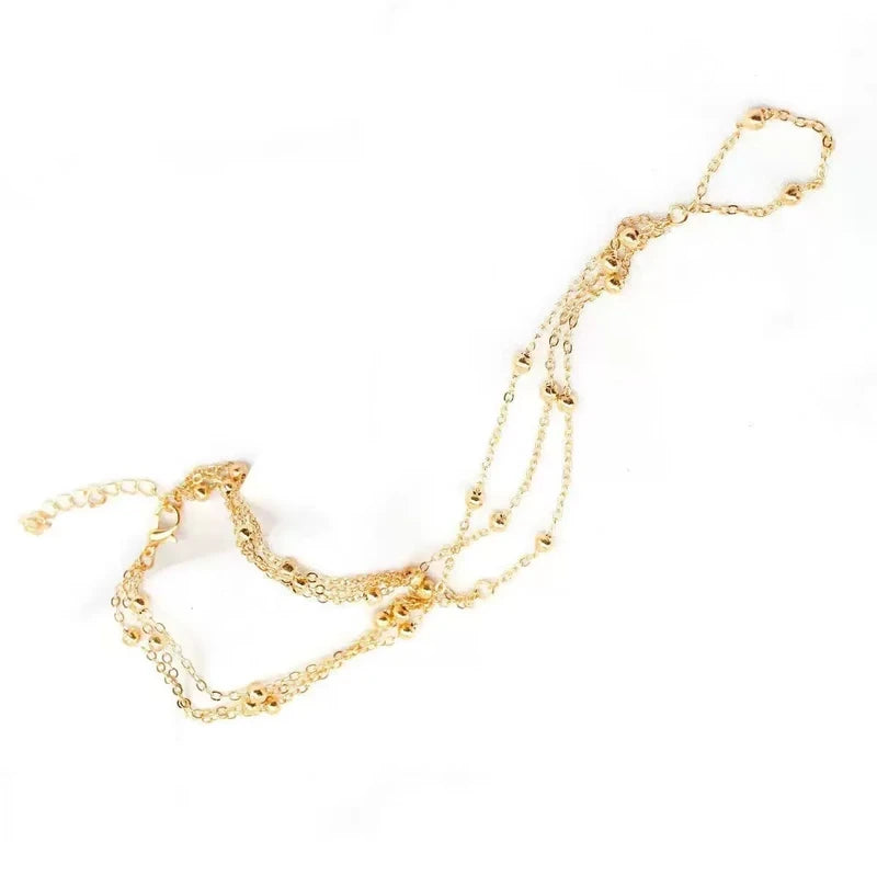 Gold beaded multi-chain anklet laid flat on a plain white background