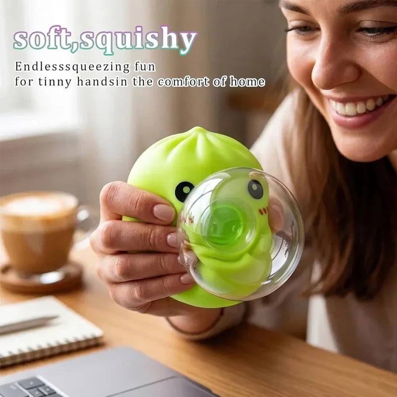 Sensory Bubble - A hand squeezes a bright green steamed bun shaped squish toy, holding it over a wooden table with a coffee cup, notebook, and laptop nearby.