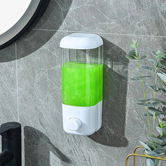 White and clear travel set bottles soap dispenser with green liquid, mounted on gray marble bathroom wall