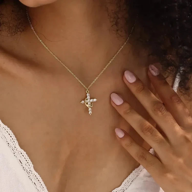 Faith Necklace - Gold crown cross pendant on fine chain worn at the collarbone, displayed against skin with a hand resting near the neckline