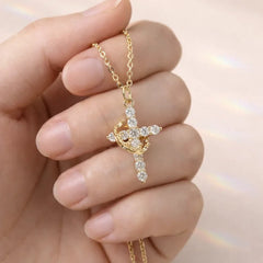 Faith Necklace - Close-up of a hand holding a gold crystal-studded cross pendant attached to a thin gold chain.