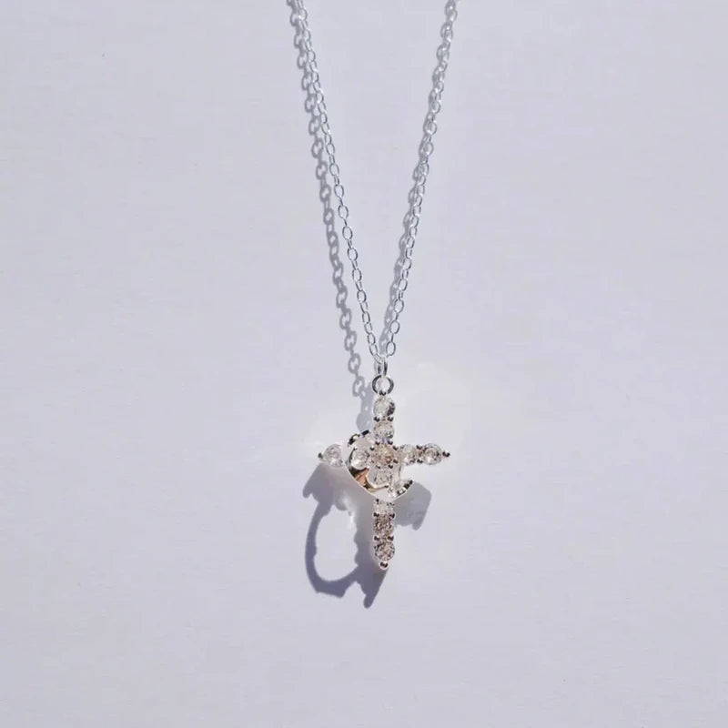 Faith Necklace - Silver-tone crystal-embellished cross pendant on silver chain, hanging against a plain light background