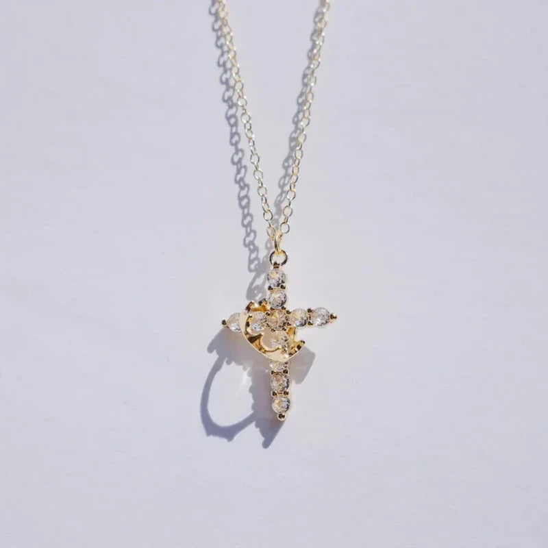Faith Necklace - Gold toned chain necklace with clear stone cross pendant wrapped in a gold crescent detail, on light plain background