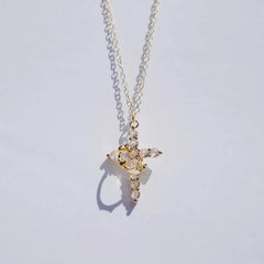 Faith Necklace - Gold toned chain necklace with clear stone cross pendant wrapped in a gold crescent detail, on light plain background