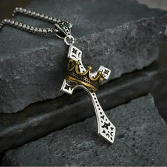 Crown Pendant - Two-tone cross design with crown accent resting on dark textured stone, attached to silver box chain