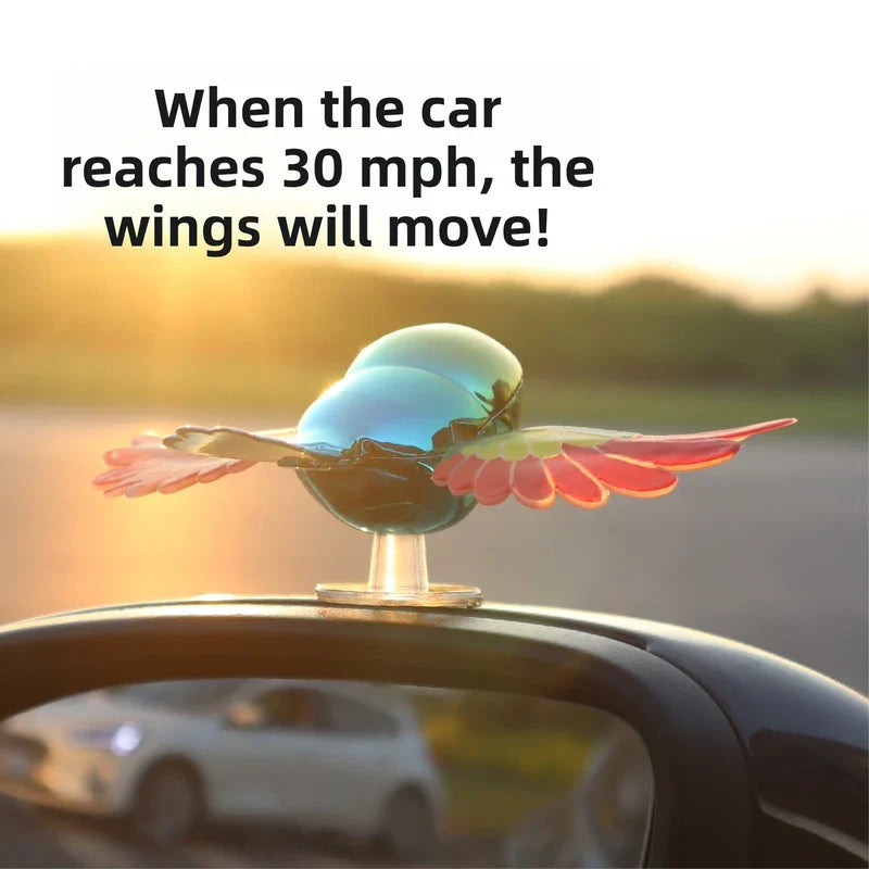Car Decoration - Iridescent hummingbird car ornament with spread red-yellow wings, mounted on a car side mirror base.