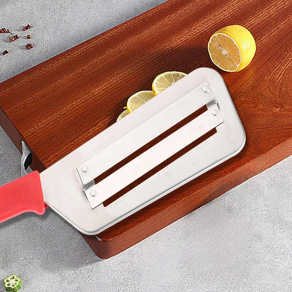 Stainless steel cabbage slicer with red handle on wooden board beside lemon slices and spices