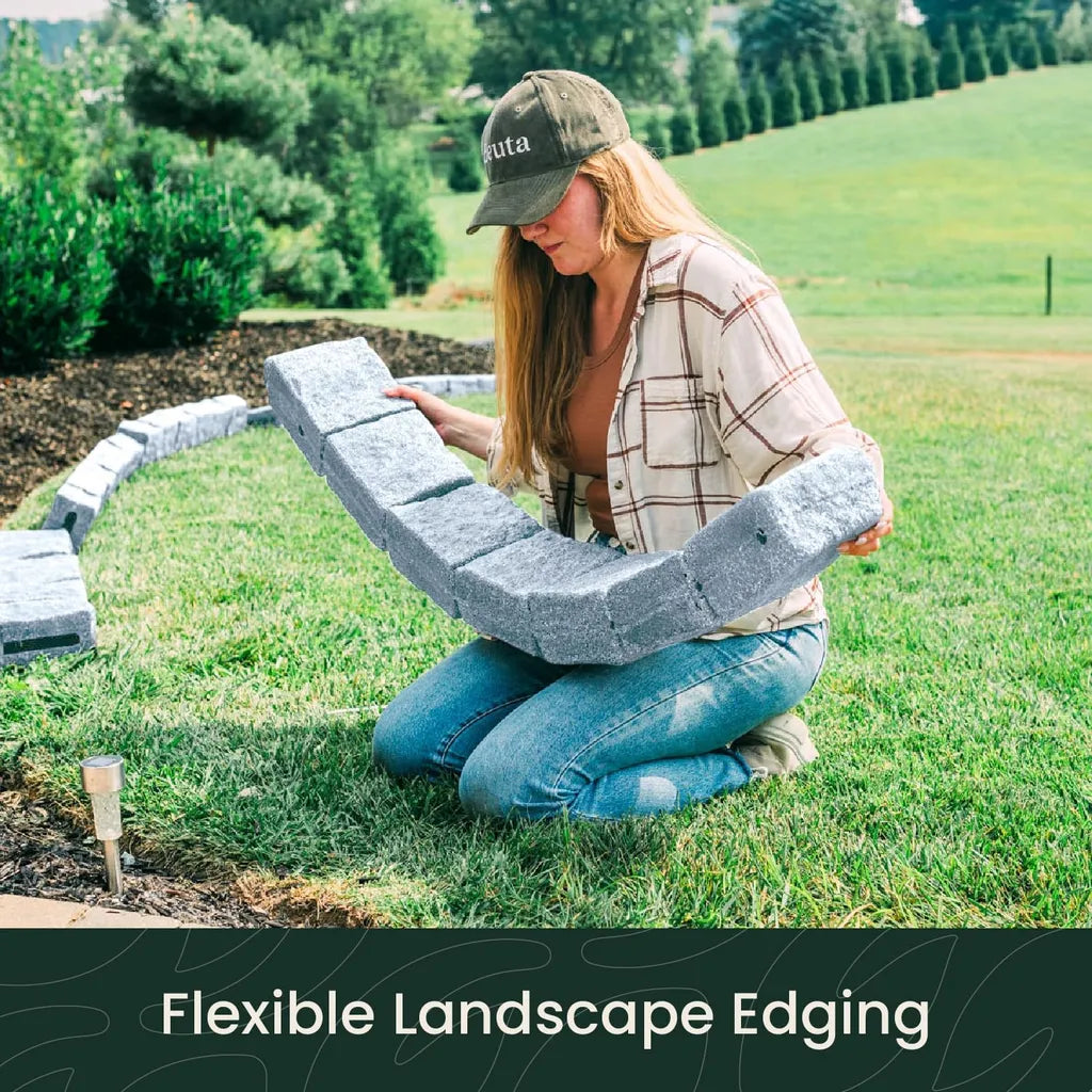 Woman installing flexible grey stone landscape edging in garden